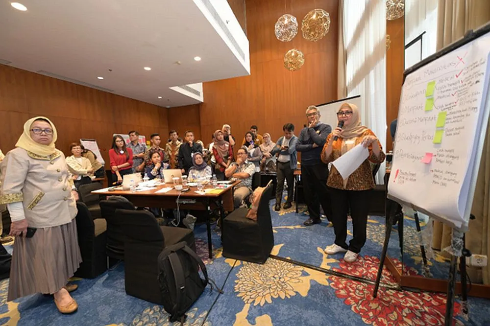 People sitting in the room listening to one person standing 