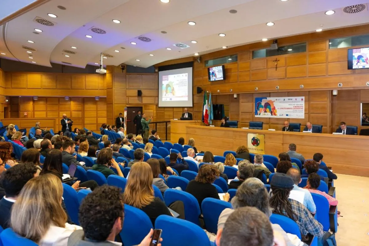 Veduta di una sala riunione con molti partecipanti seduti.