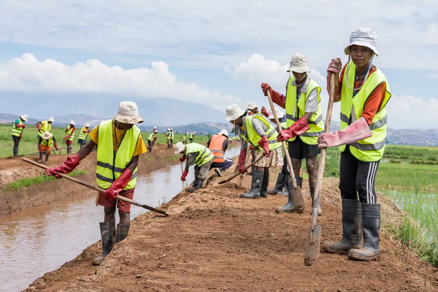 workers in protective gear clearing an irrigation ditch