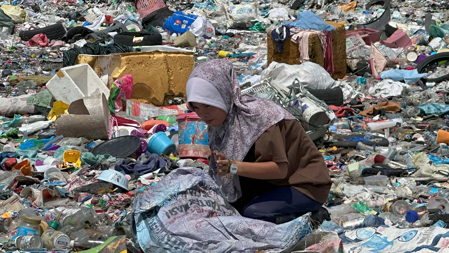 a young woman wearing hijab scavenging in the dumpsite