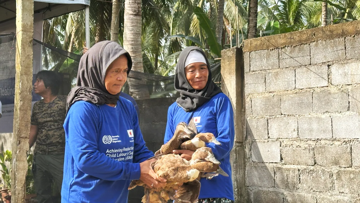 two women holding and taking care of ducks