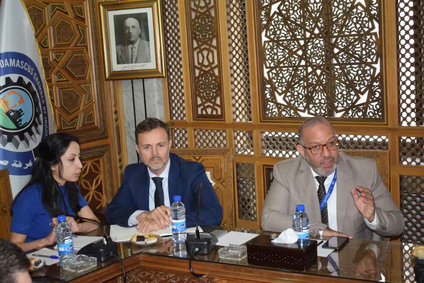 A woman and two men at a meeting at the Damascus Chamber of Industry