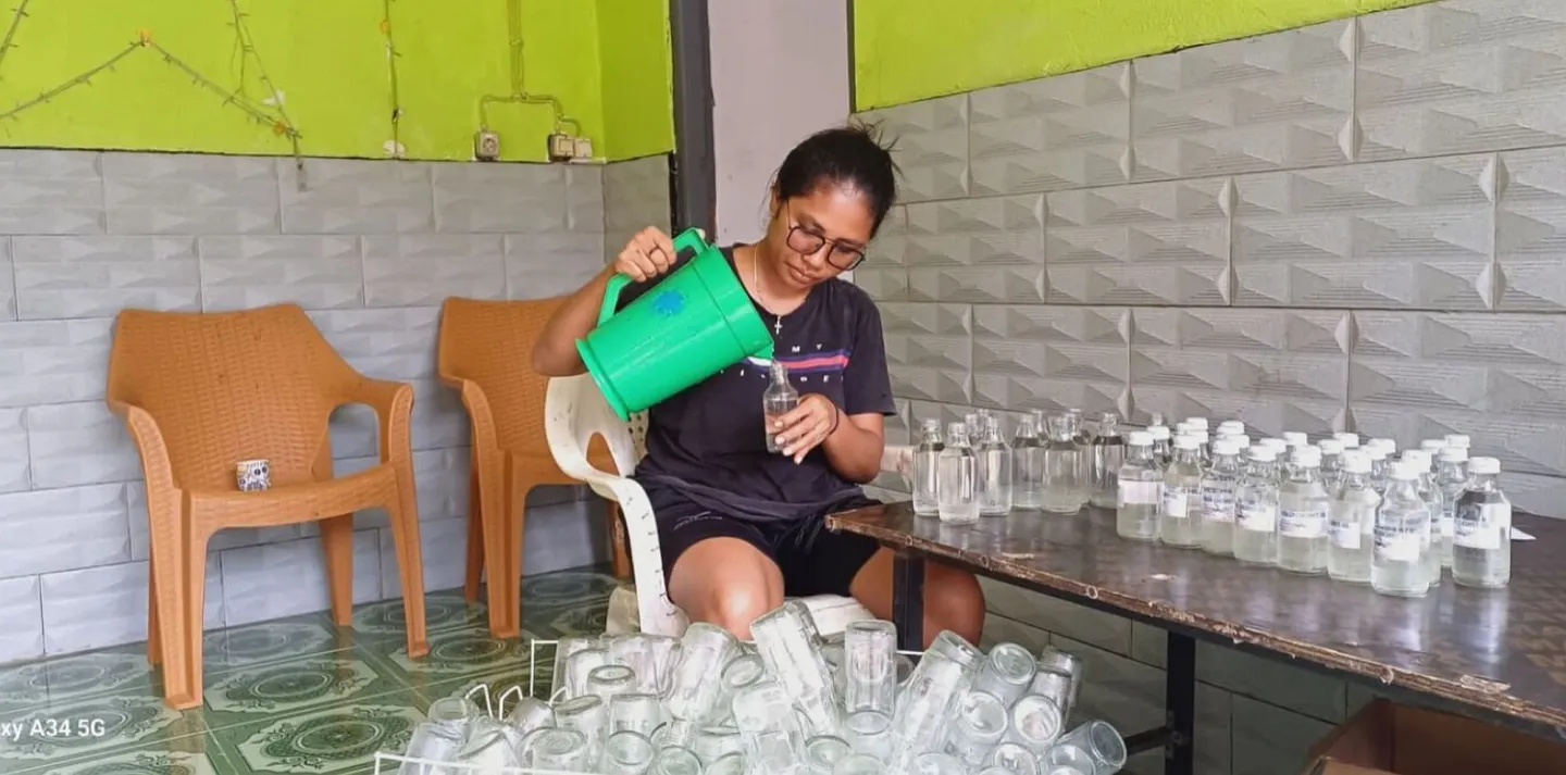 A woman filling in empty bottles with VCO