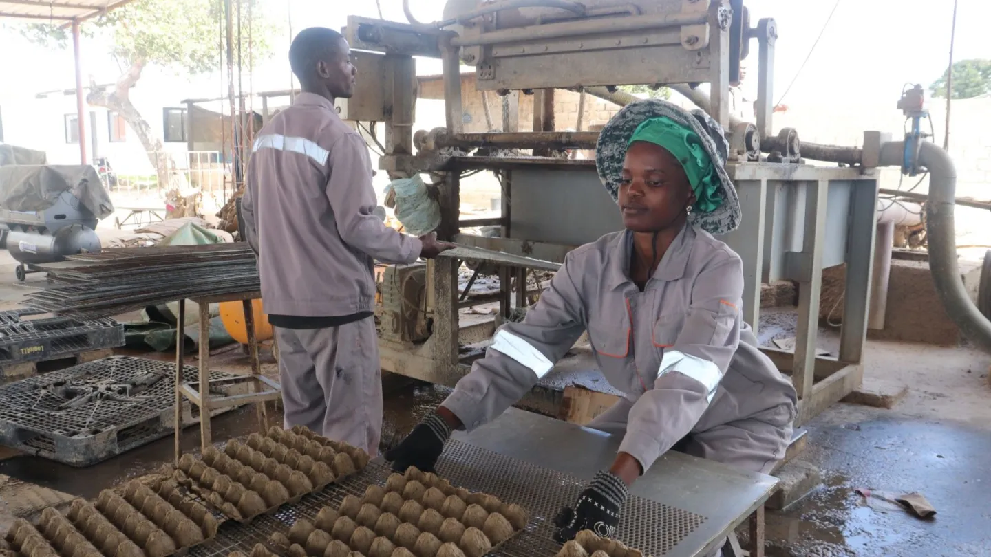 Delfina and Lutehi operating egg making machine at the factory. 