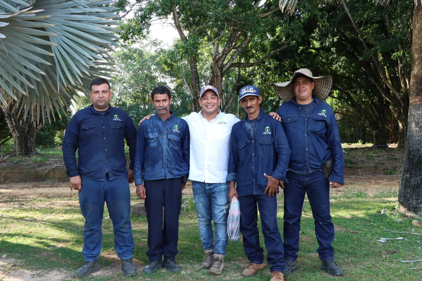 Foto de cuatro trabajadores uniformados posando sonrientes junto a su empleador.