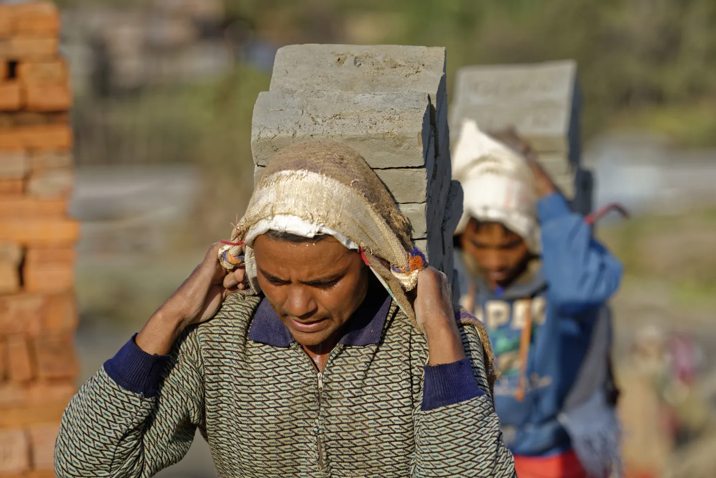Two men carrying pieces of bricks in the suburbs of Kathmandu, Nepal.