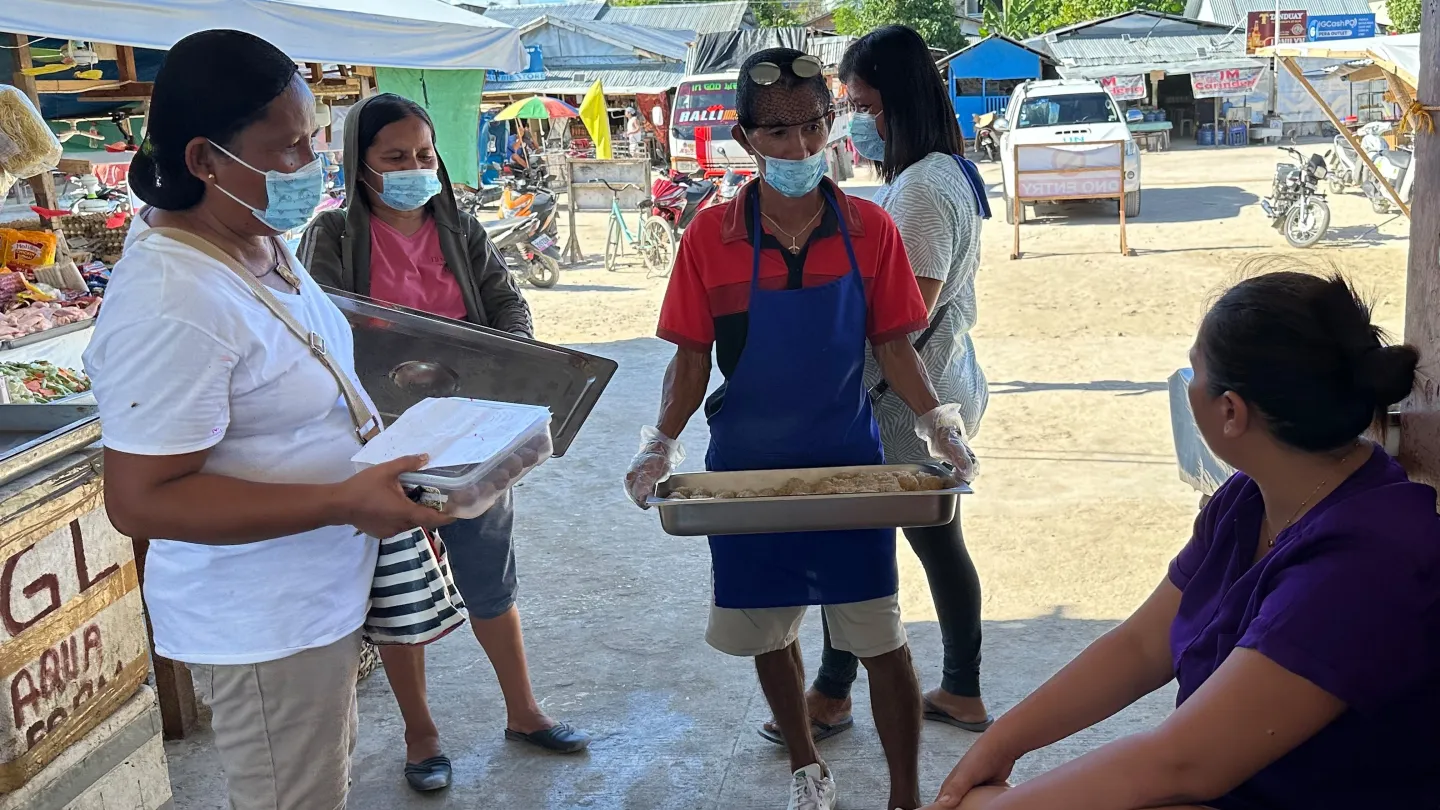 People sell coconut products in a public market.