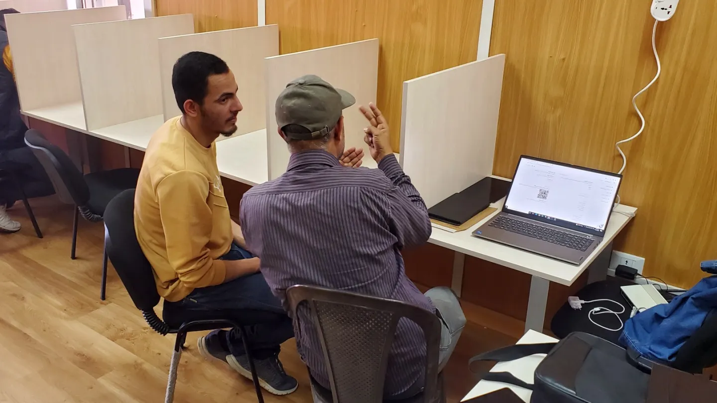 Ahmed sits with his father Abdel Latif during the final exam of the RPL project. Abdel Latif helps clarify the meaning of the questions for his son