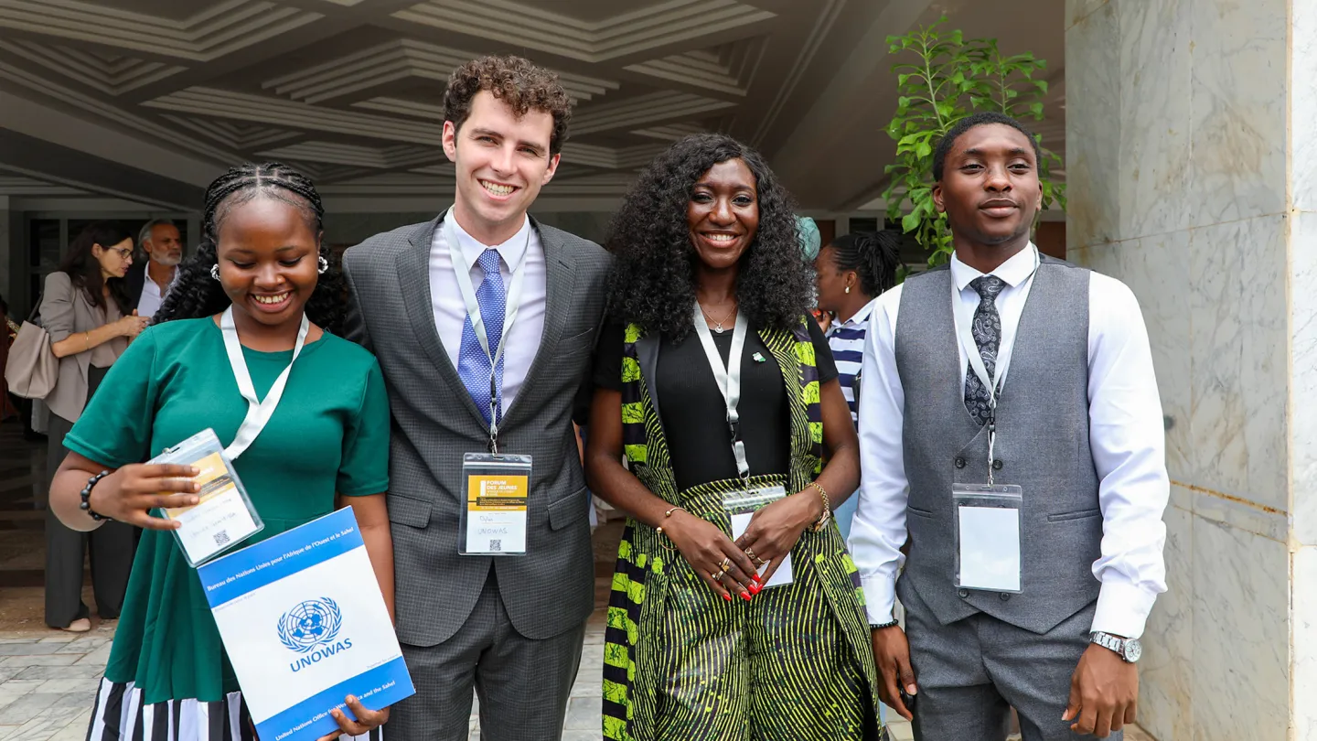 Four youth delegates at the 4th Annual West Africa and Sahel Youth Forum in Dakar smile for the camera outside the conference venue.