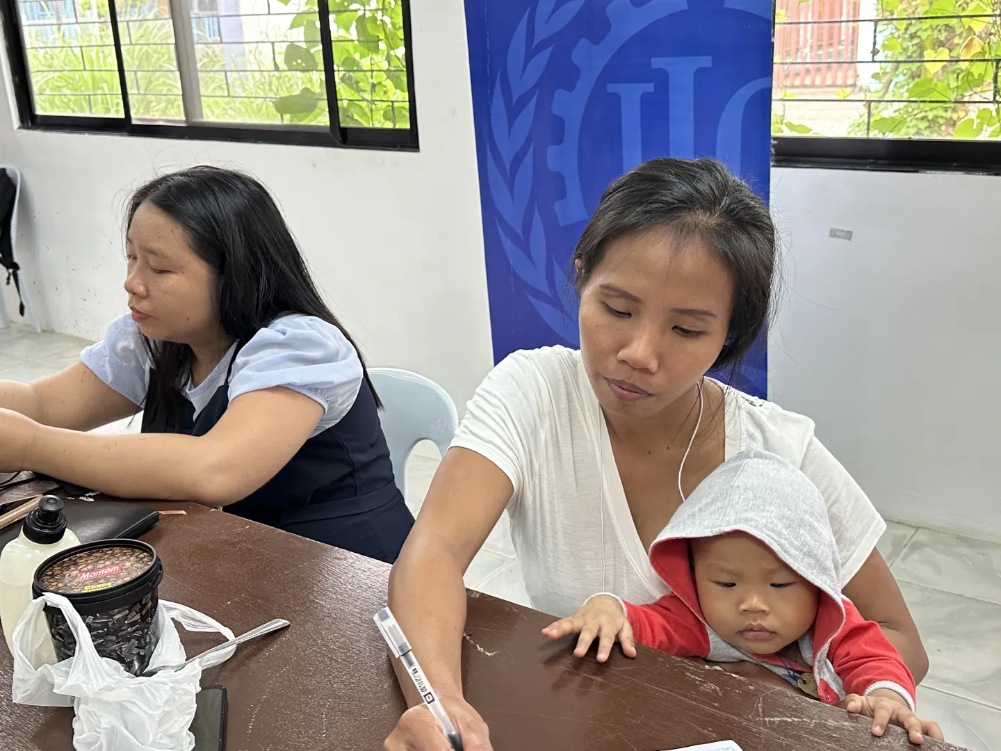 a woman writing while carrying her baby