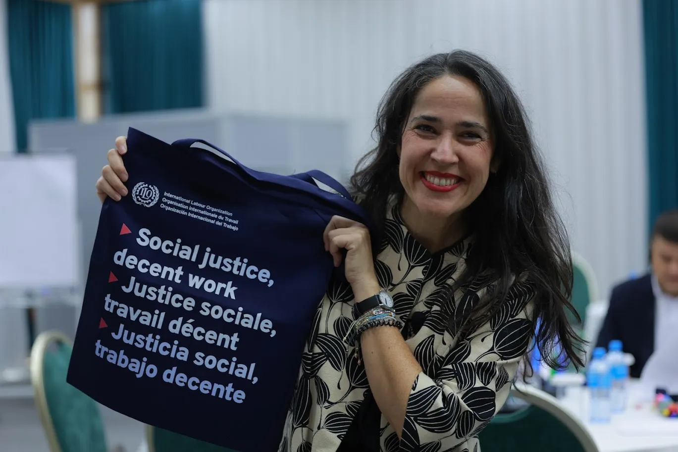 A woman smiling and holding an ILO bag