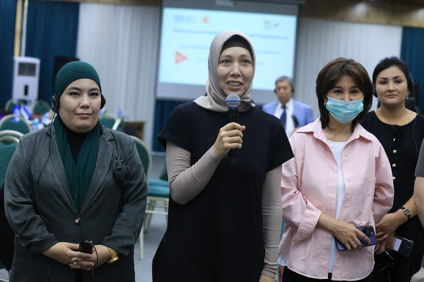 Group of women standing, one with a mic