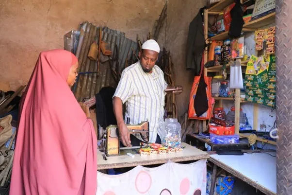 Mohamed Sheikh Gudoow, a trader and a father of five, serving a customer at his shop in Sigaale Market 