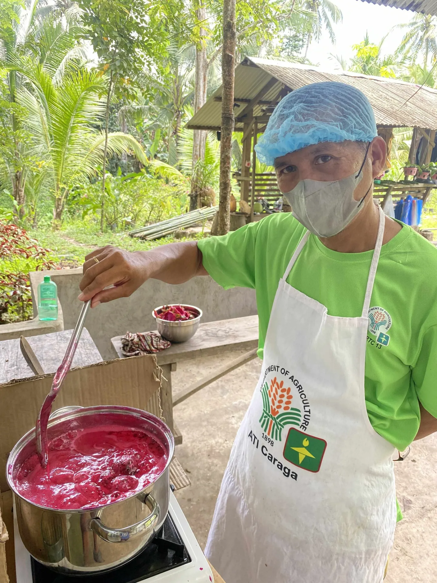 A man cooking dragon fruit jam wearing an apron