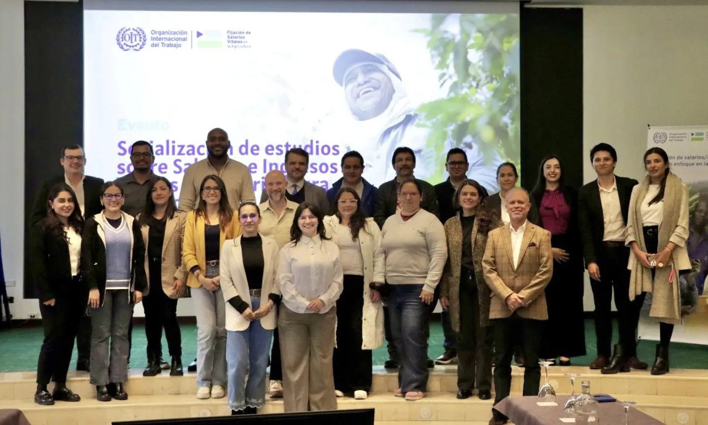Veintidos personas (10 hombres y 12) posan para la foto del evento en las escaleras del salón con la pantalla de fondo. 