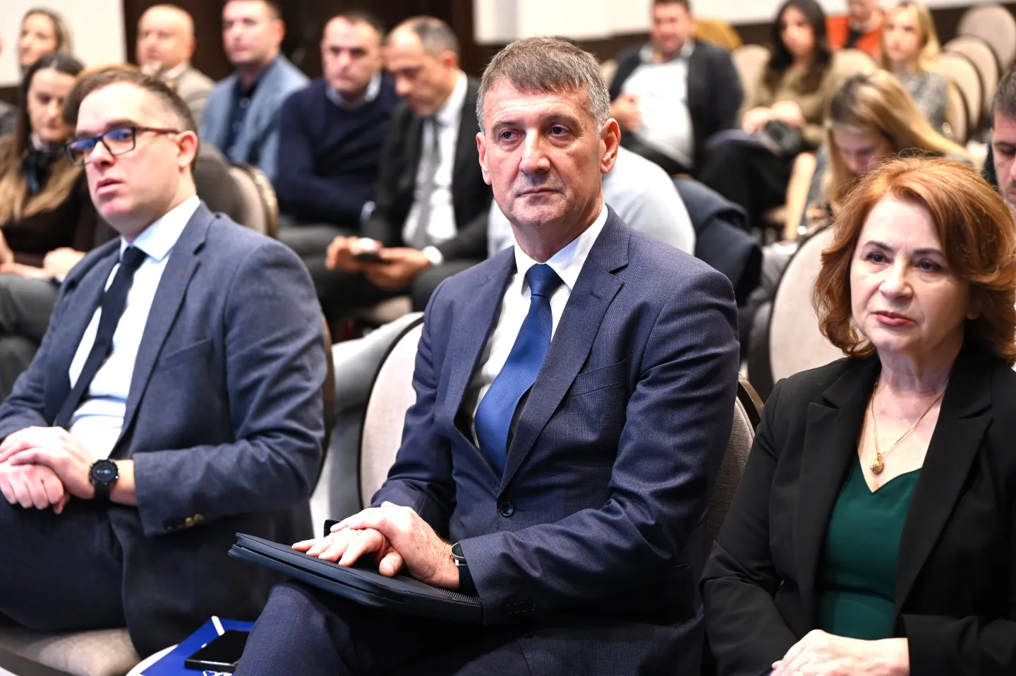 Two men and a women sitting in the first row of the auditorium. The men are Montenegro's employers' president and secretary general.