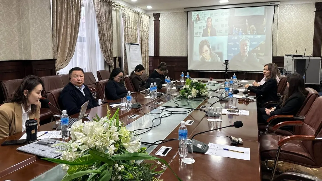 People sitting at a table looking at a big screen