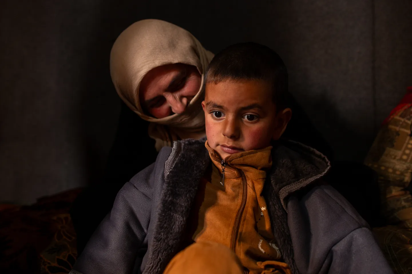Syrian agricultural worker Aisha Al Mohammed and her youngest son sit inside a tent in their informal settlement in Lebanon’s Bekaa Valley. December, 15, 2025 