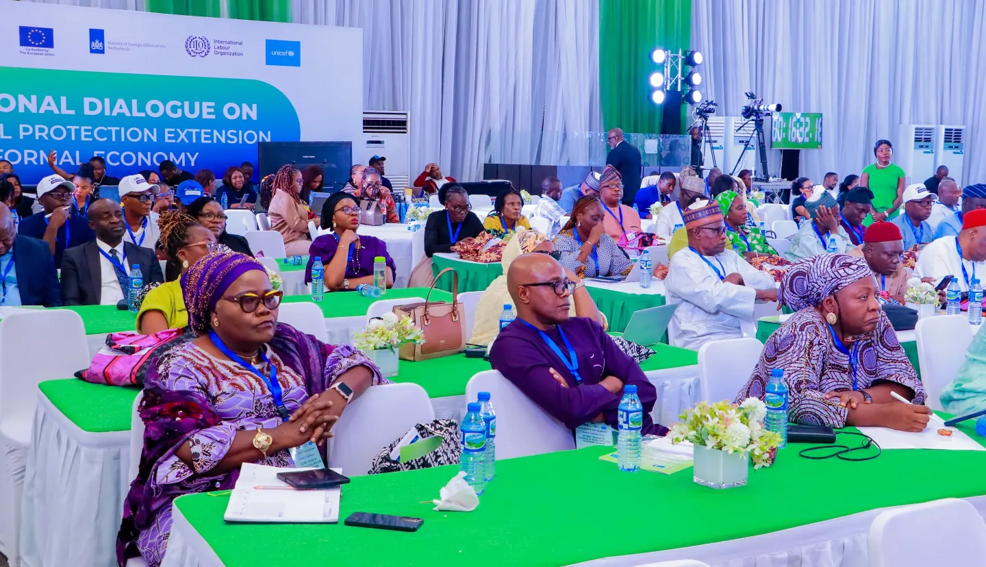 Attendees are seated in rows, listening attentively to the proceedings of the National Dialogue on Social Protection Extension to Informal Economy Workers