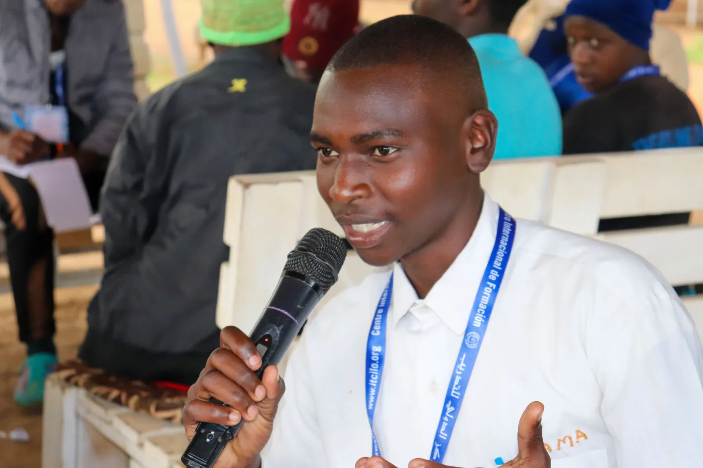 Emmanuel speaks into a microphone during a group discussion at the Mbale child labour hackathon.