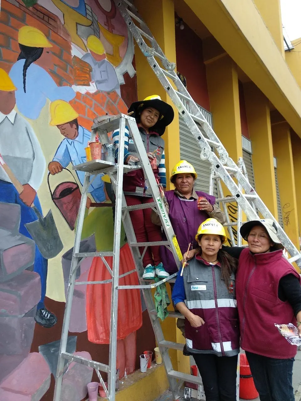 Bolivian women on a mural painting that they completed