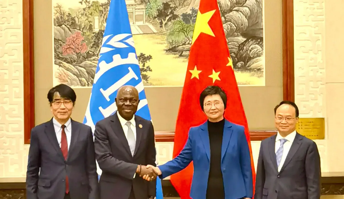 Gilbert F. Houngbo, Director-General of the ILO, with Wang Xiaoping, Minister of Human Resources and Social Security of China shaking hands in front of their flags