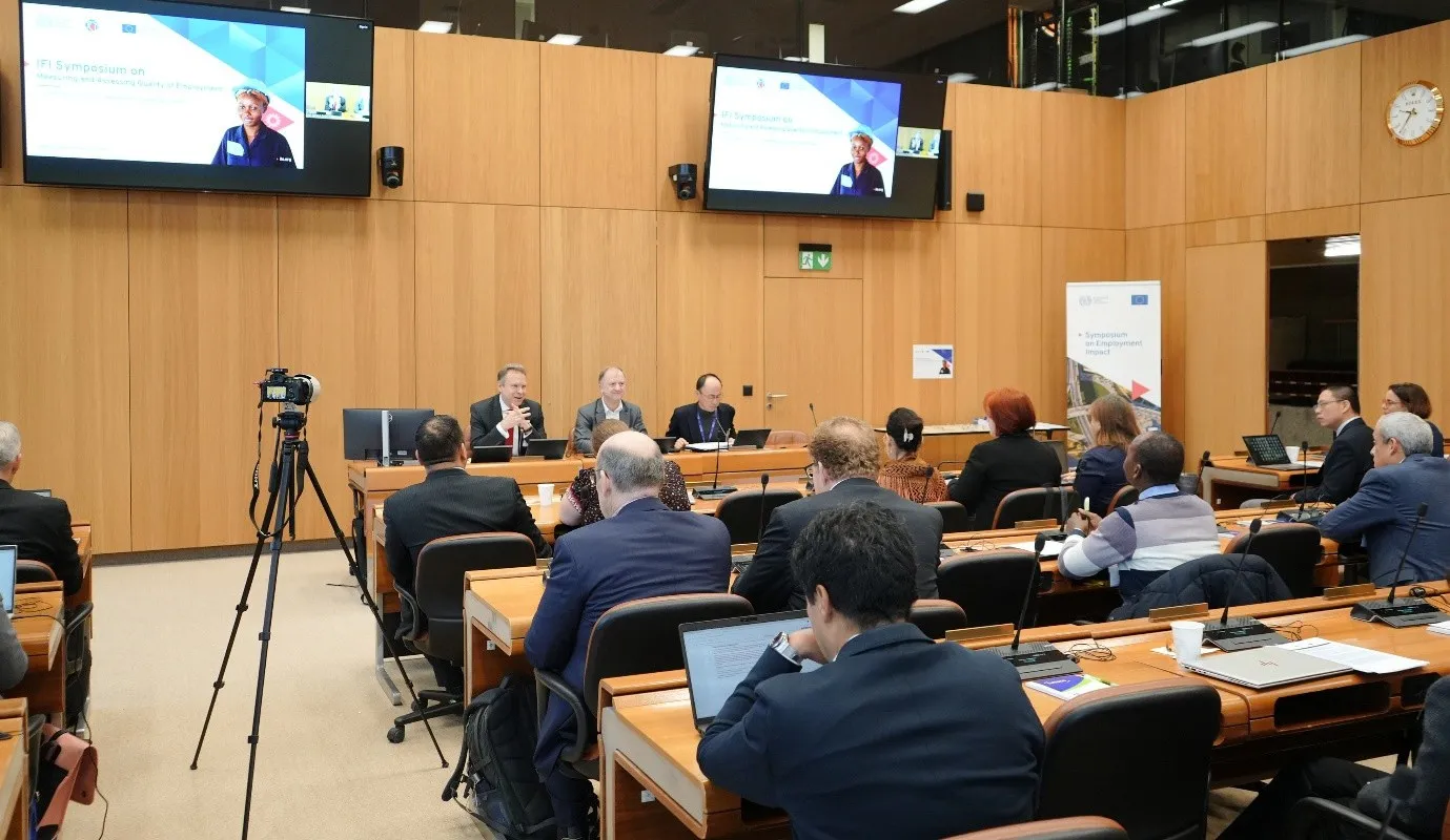 panel of 3 men and an audience in a meeting room.