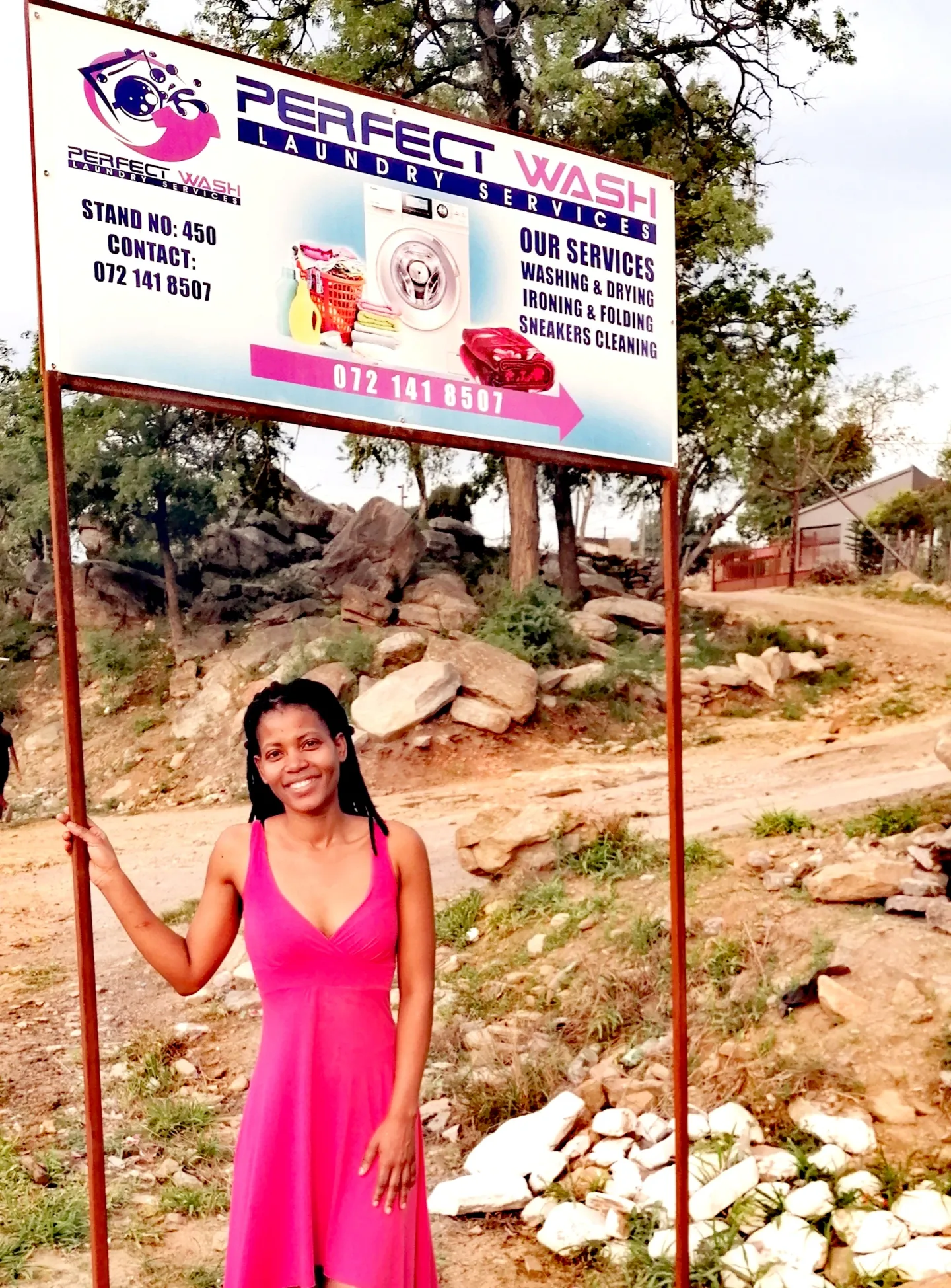 South African woman under an advertising sign for her laundry services company