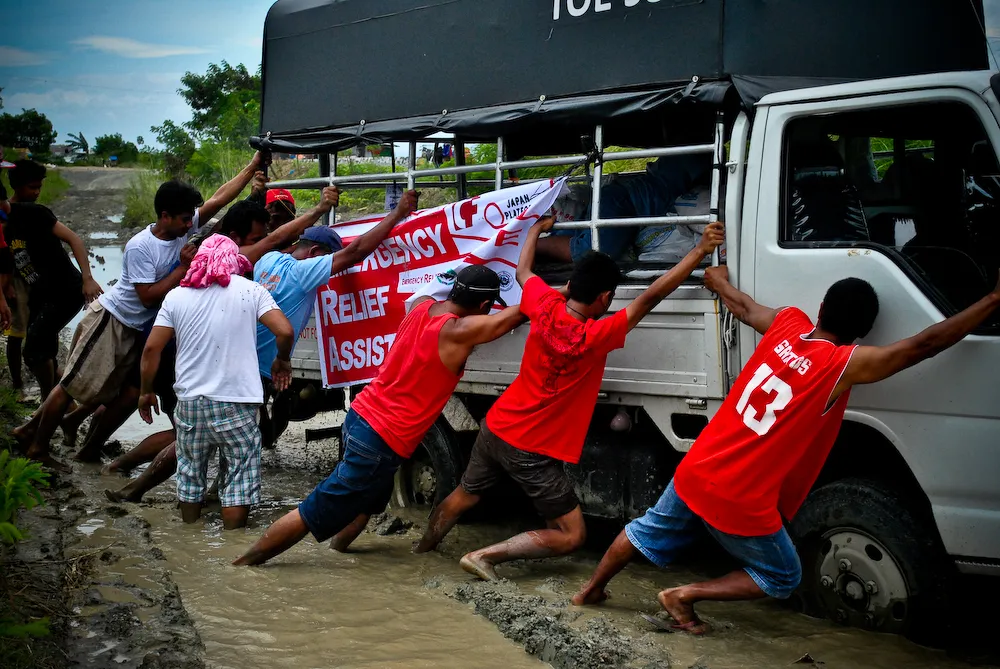 A group of volunteers helping a truck get out of the mud