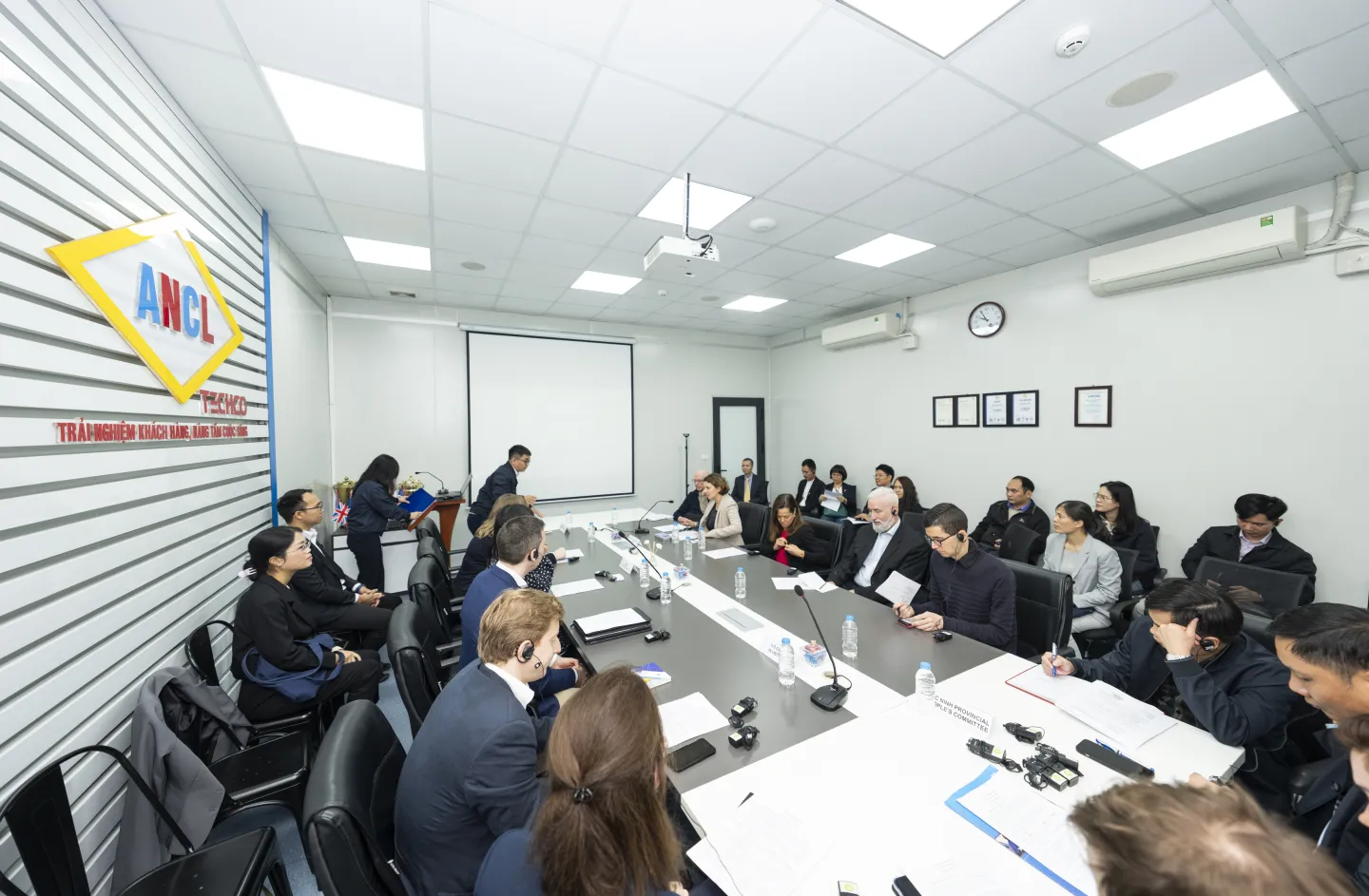Members of the delegation meet with management and staff of ANCL TECHCO in Bac Ninh province, seated around a conference table during a factory visit to discuss productivity improvements and work organization.