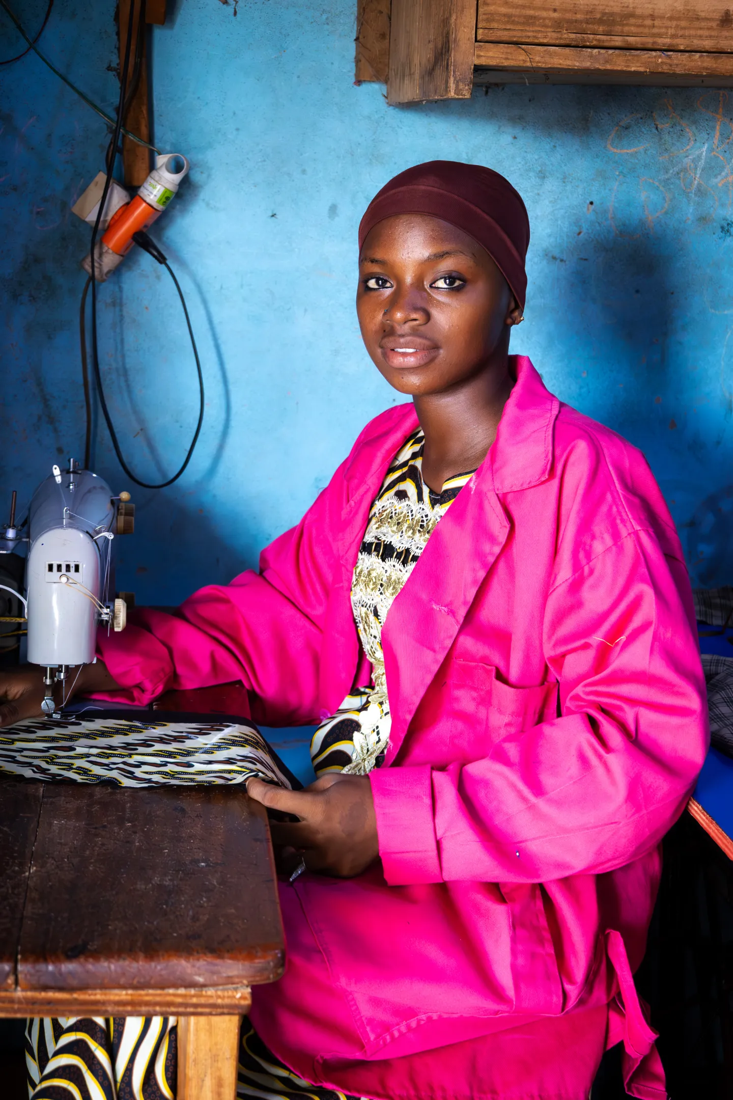 Coulibaly Aminata sourit, assise à une machine à coudre dans un atelier à Grand-Zattry, en Côte d’Ivoire.