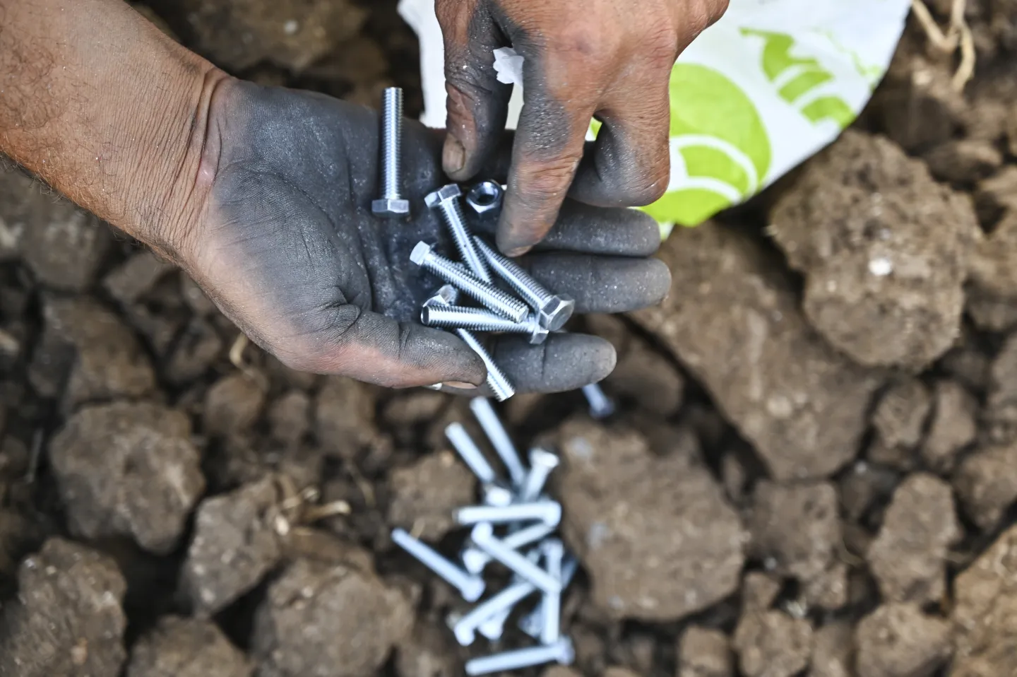 A greenhouse installer inspects screws before continuing assembly. 