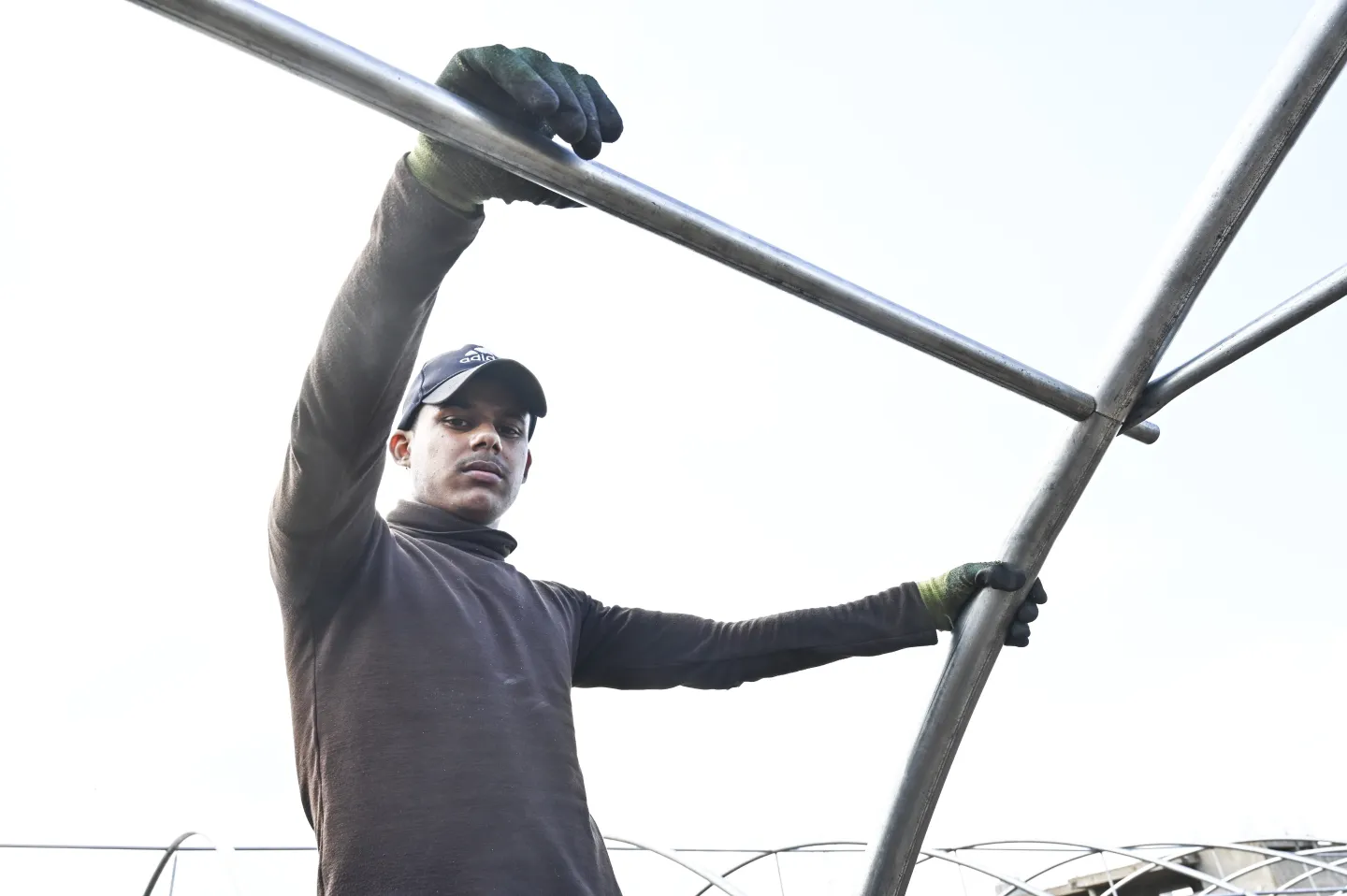 Installer at work constructing a greenhouse frame. 