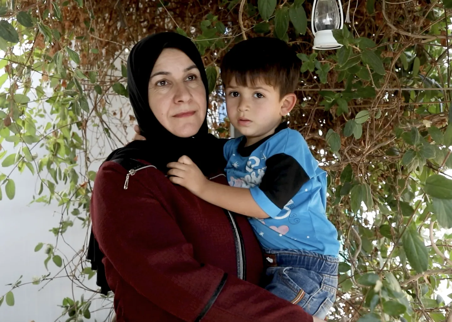 Tailor Malika Abdel-Rahim Al-Haraki holds and hugs her three-and-a-half-year-old son, Shady, in the patio of their home in Jordan’s Za’atari camp for Syrian refugees on October 28, 2025.