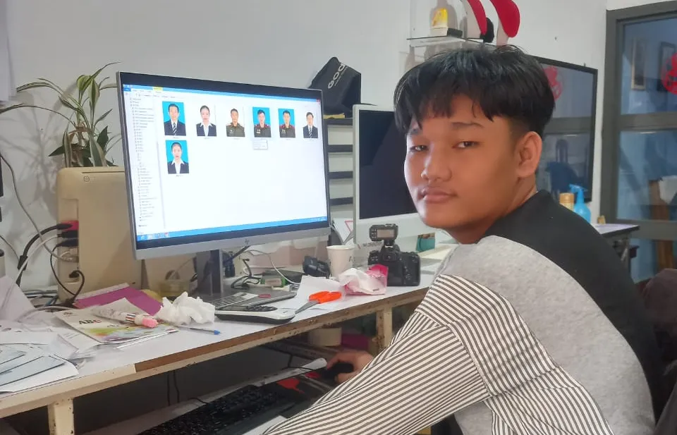 A man working on a computer, with photos displayed on his screen.