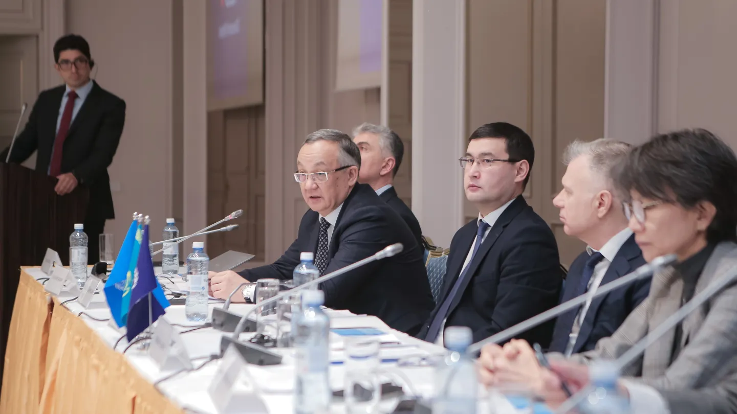 Group of people sitting at a table, one of them speaking into the microphone