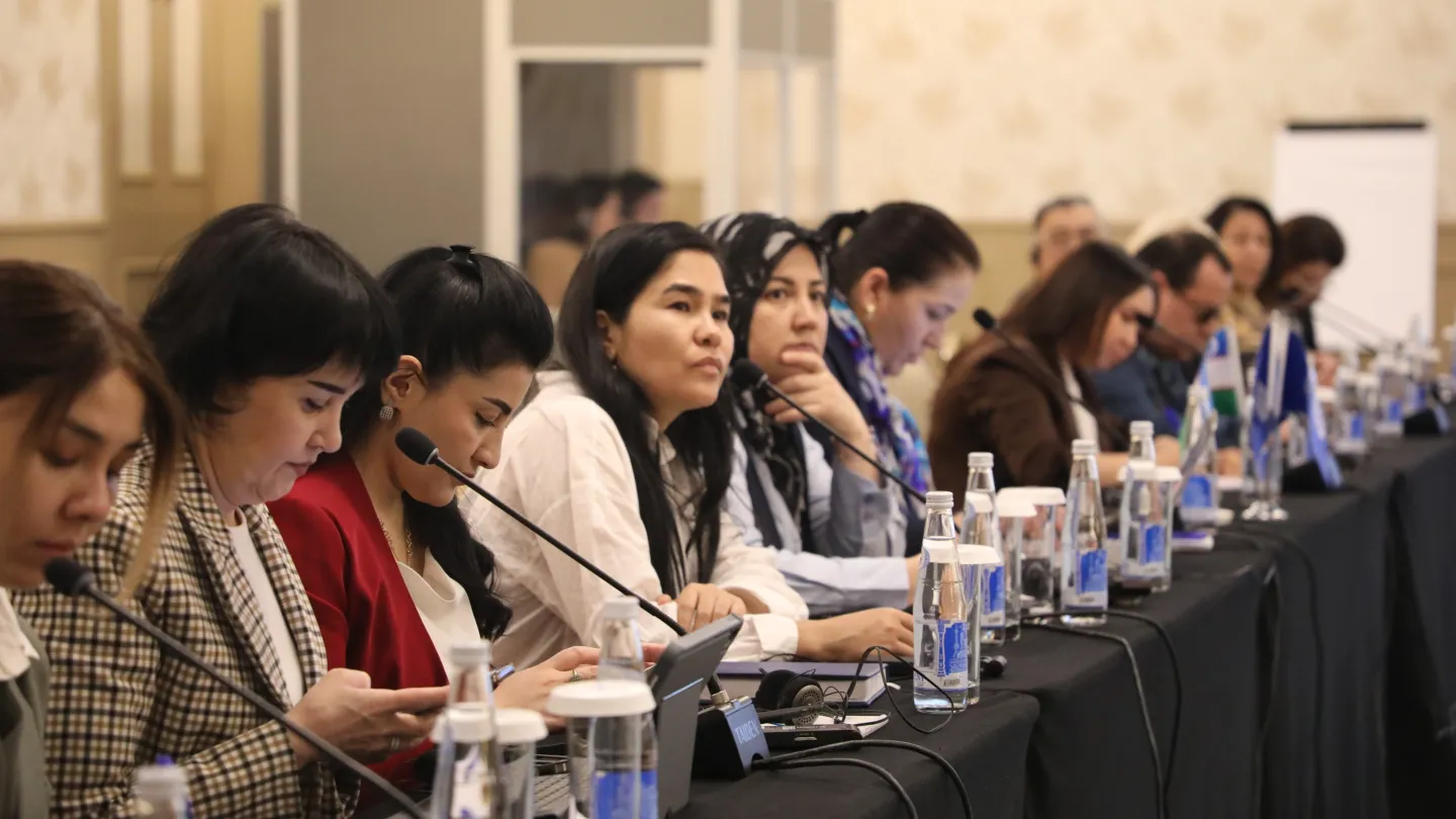Participants seated at a conference table listening during a roundtable discussion