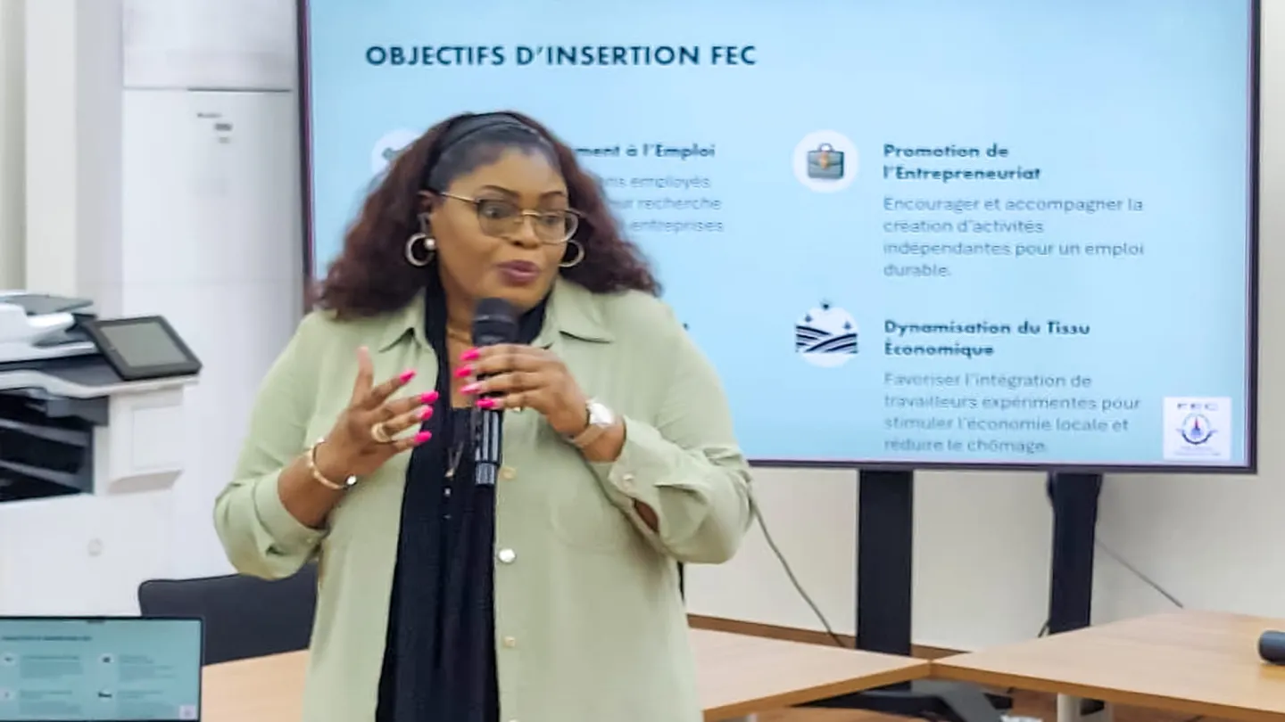 Malou Nzuzi, Vice-Présidente Développement des compétences de la Commission Nationale Sociale et Employabilité de la FEC, s’exprime lors de la séance, tenant un micro devant un écran présentant les objectifs d’insertion.