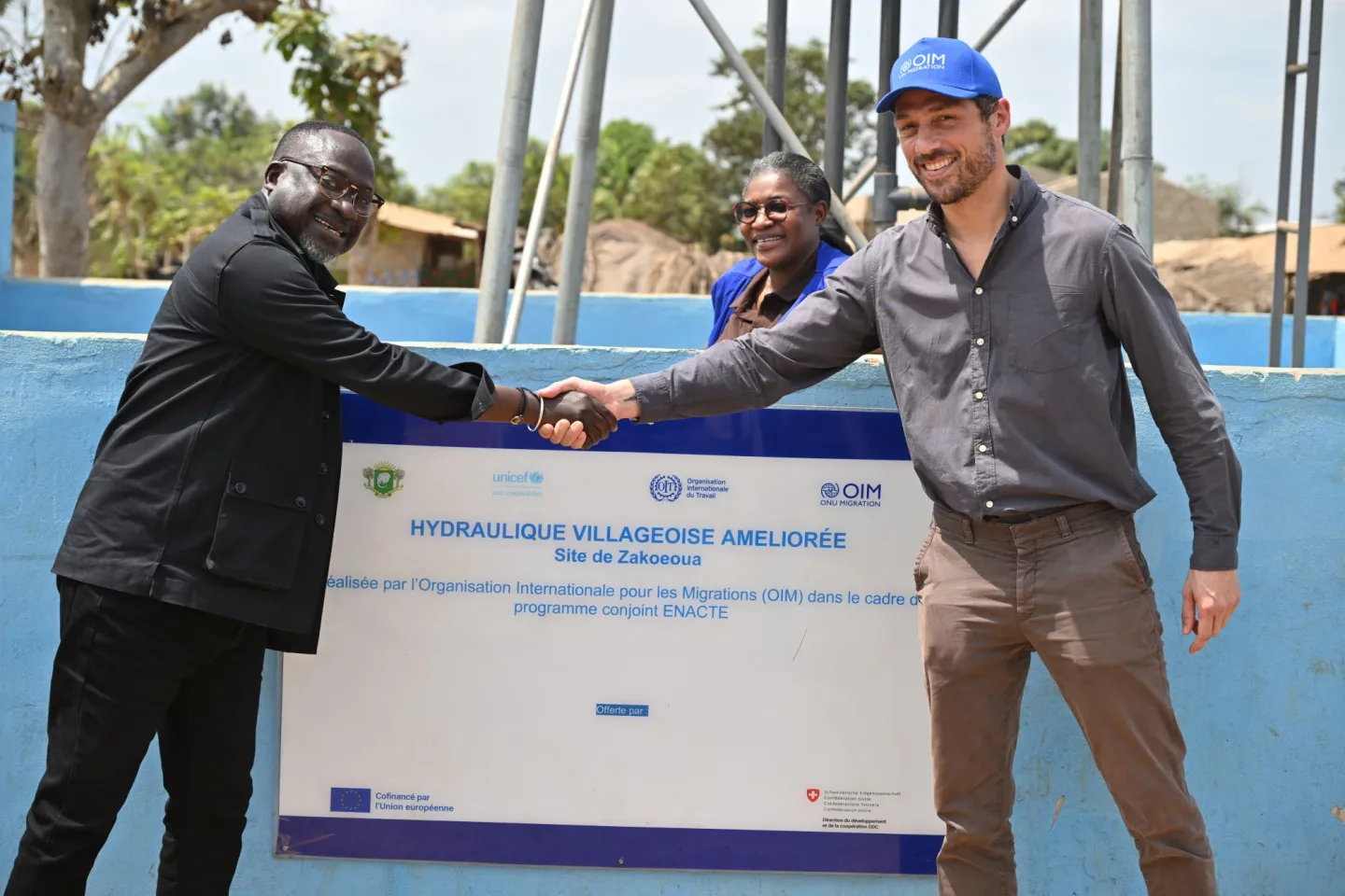 Le Représentant de l’UNICEF, Jean-François Basse (à gauche), et le Chef de Mission de l’OIM, David Preux, échangent une poignée de main à l’occasion de l’inauguration d’un ouvrage d’hydraulique villageoise améliorée au village de Zakoéoua, dans la région de la Nawa.