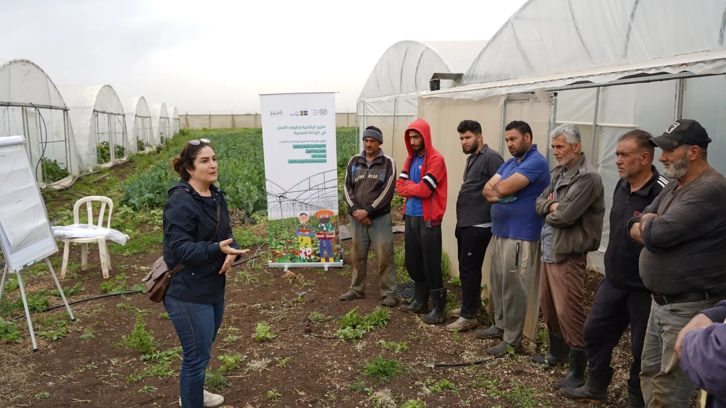 A trainer addresses farmers during an on-site awareness-raising session on upgraded greenhouse structures. 