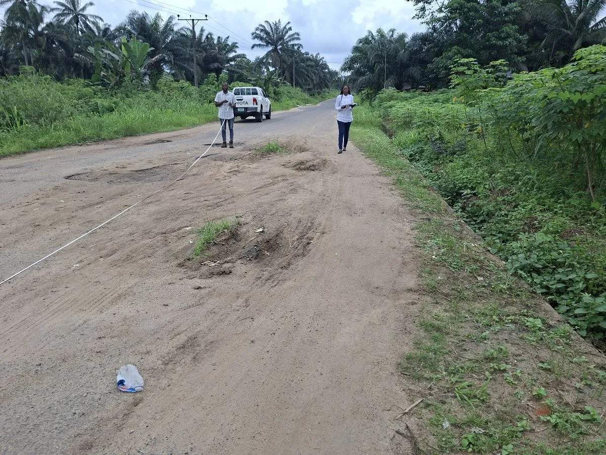 Two people on a dirt road taking measurements.