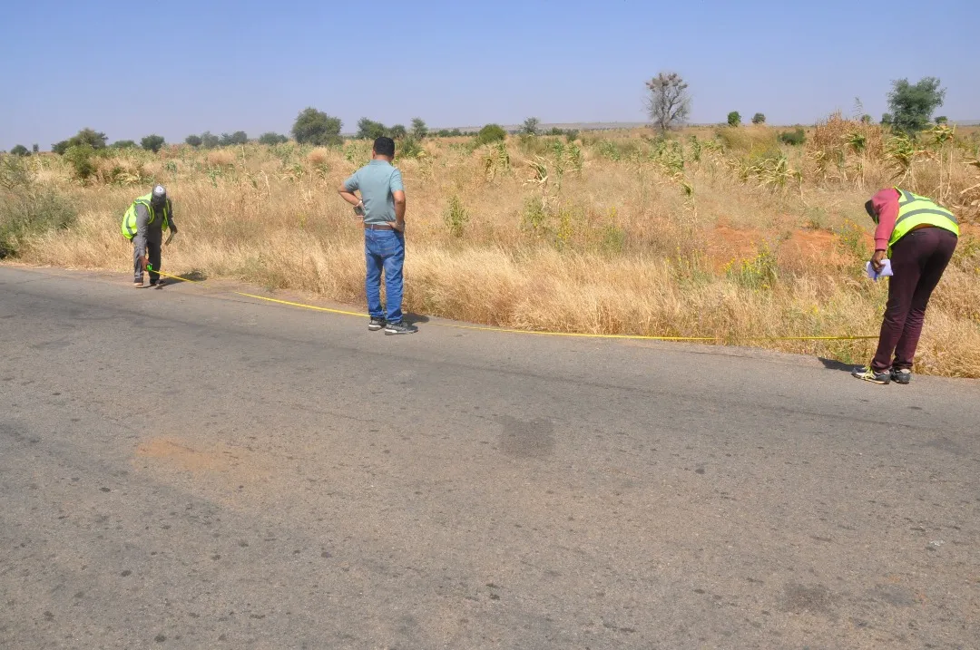 Three people at the edge of a road taking measurements