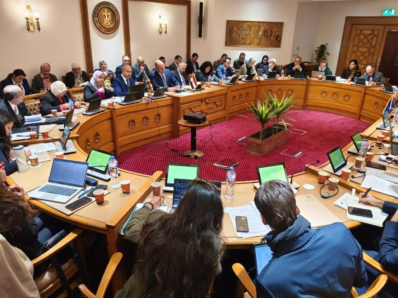 A meeting room shows a roundtable desk with people seated all around.