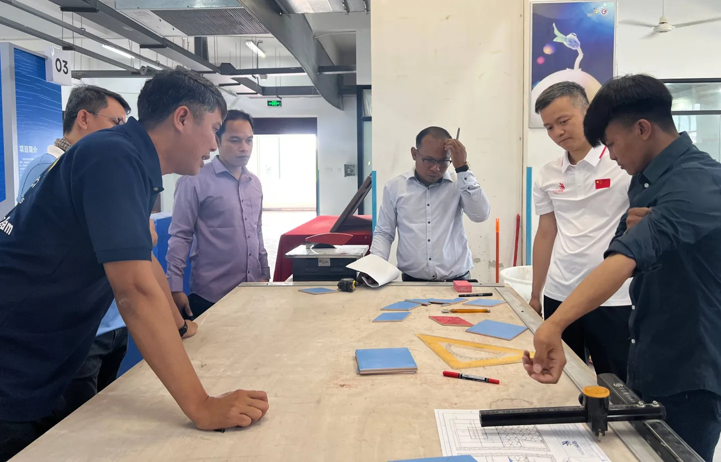 A group of people standing around a table with materials displayed on it.
