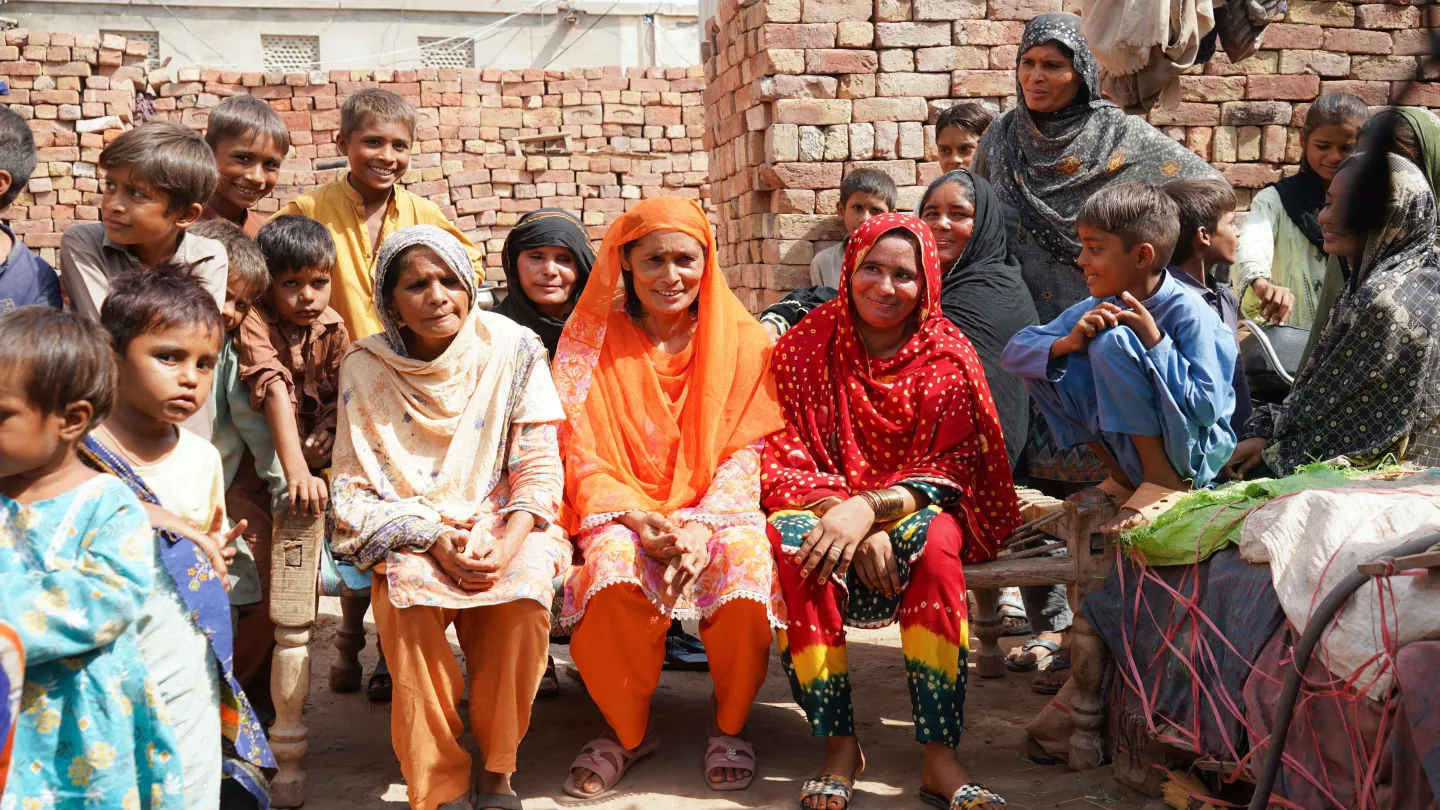 Hafeeza Mai sits outside her home with other women and their children.