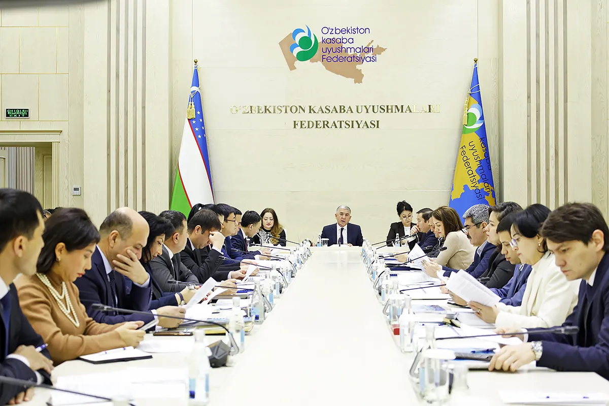 A conference room with participants seated on both sides of a long table
