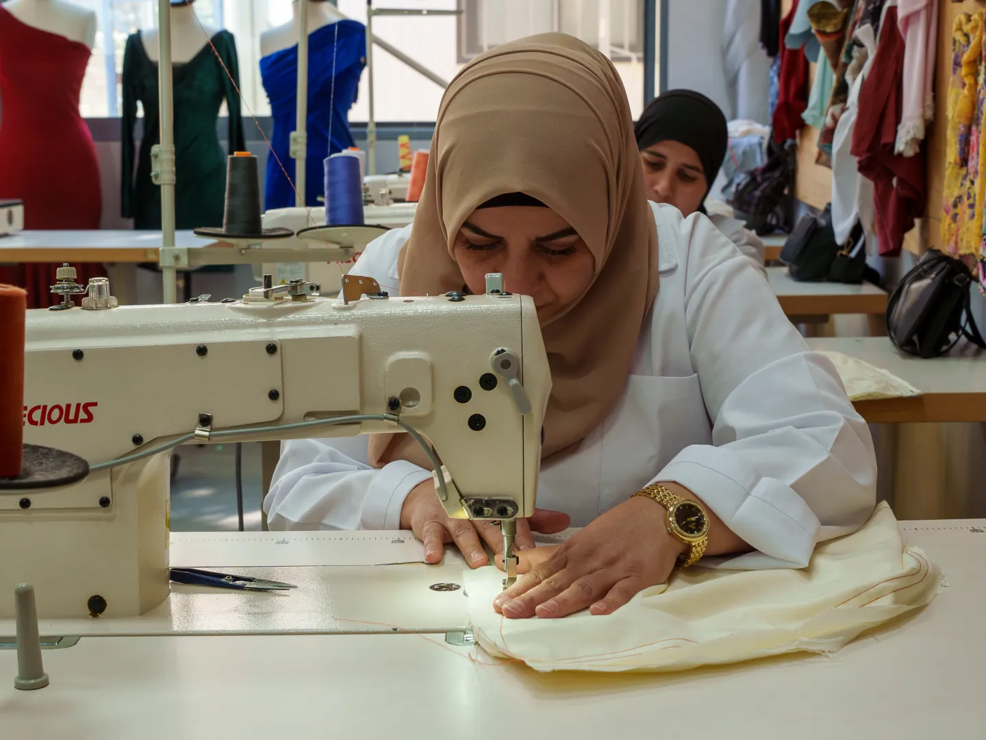 a femal worker wearing a veil and using a a sewing machine.