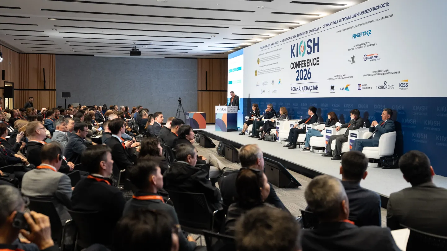 Wide conference room with seated participants facing a panel of speakers