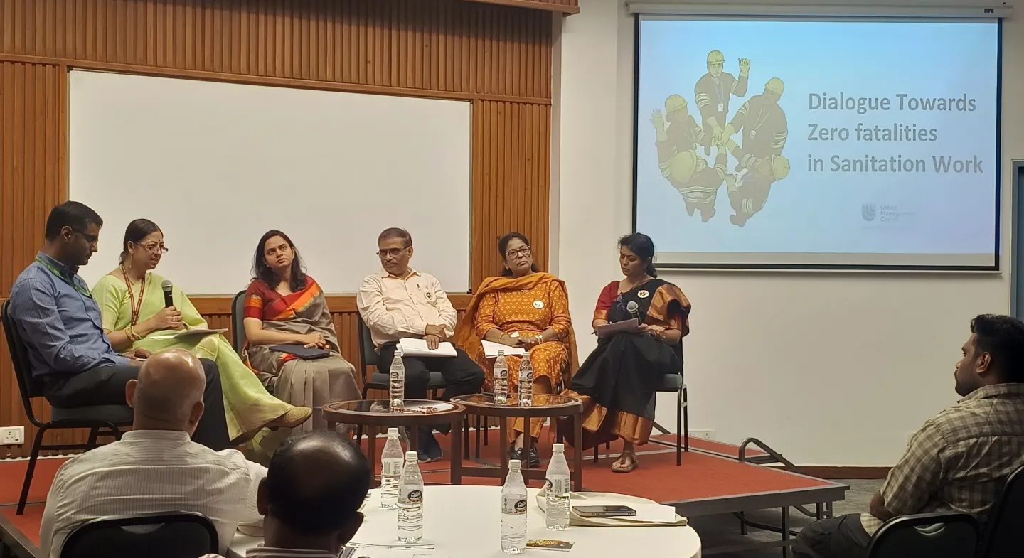 Six people seated on a stage holding microphones during a panel discussion.