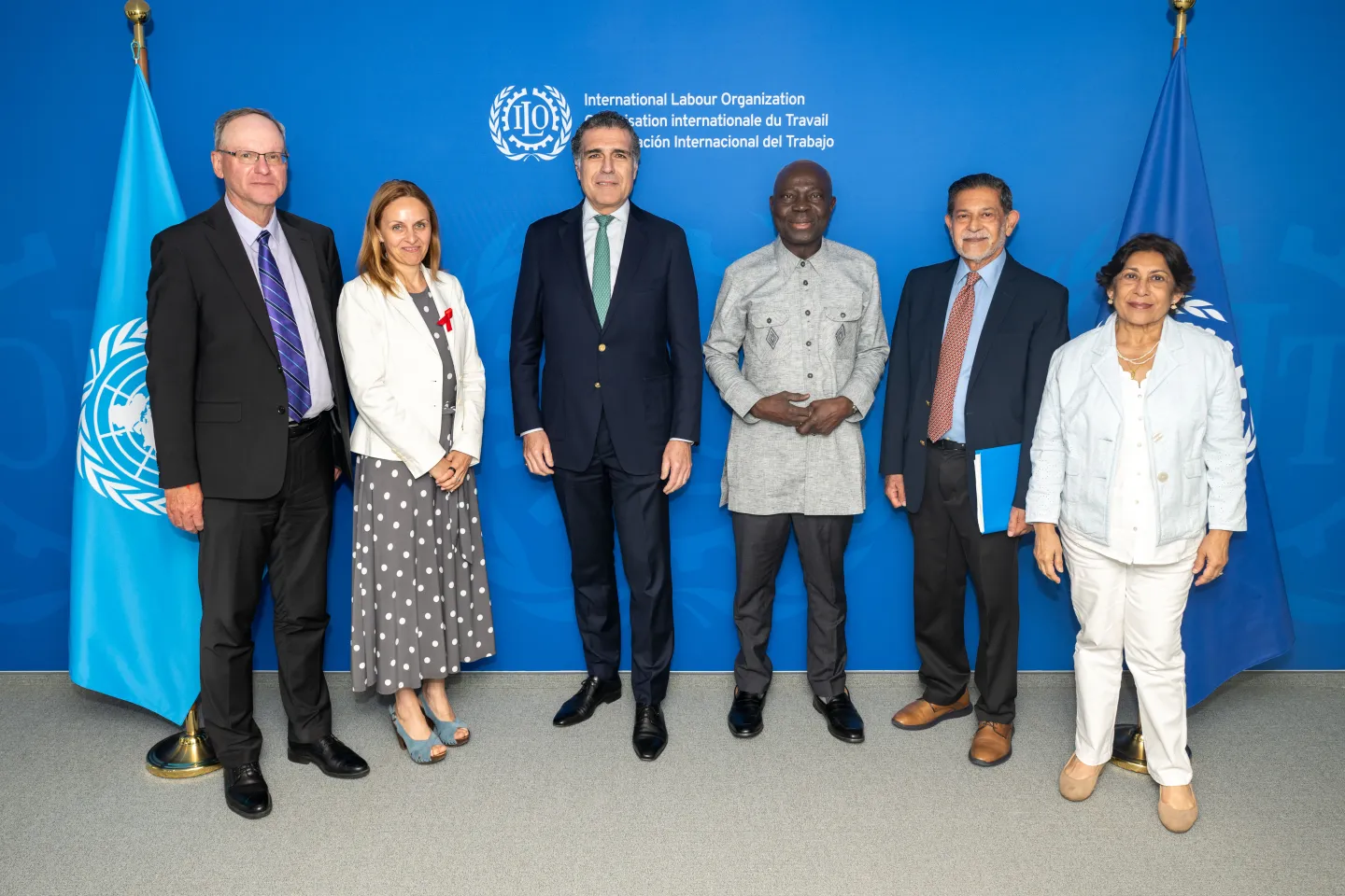 Group of six people (4 men and 2 women) standing between the UN and the ILO flags with the ILO logo and name above them